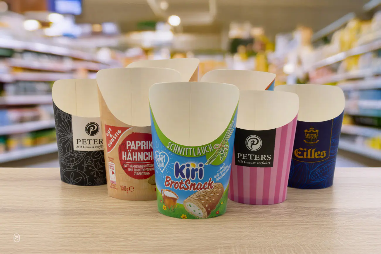 Auf einem Tisch stehen individuell gestaltete Verpackungen, im Hintergrund erkennt man Supermarktregale