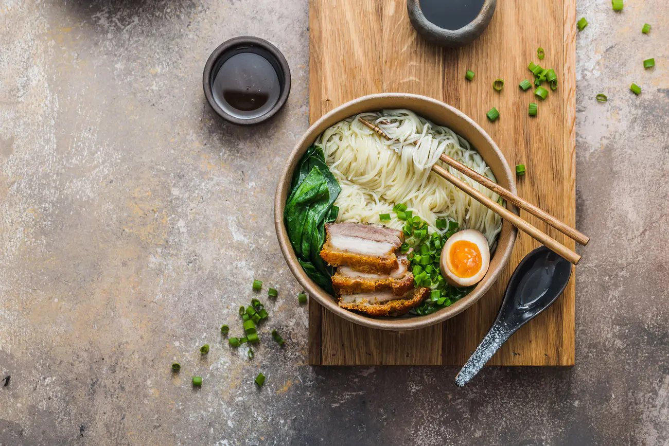 Eine G2G-Schale aus kartonbeschichtetem PE, gefüllt mit Rahmensuppe, wird auf einem Holzbrett serviert