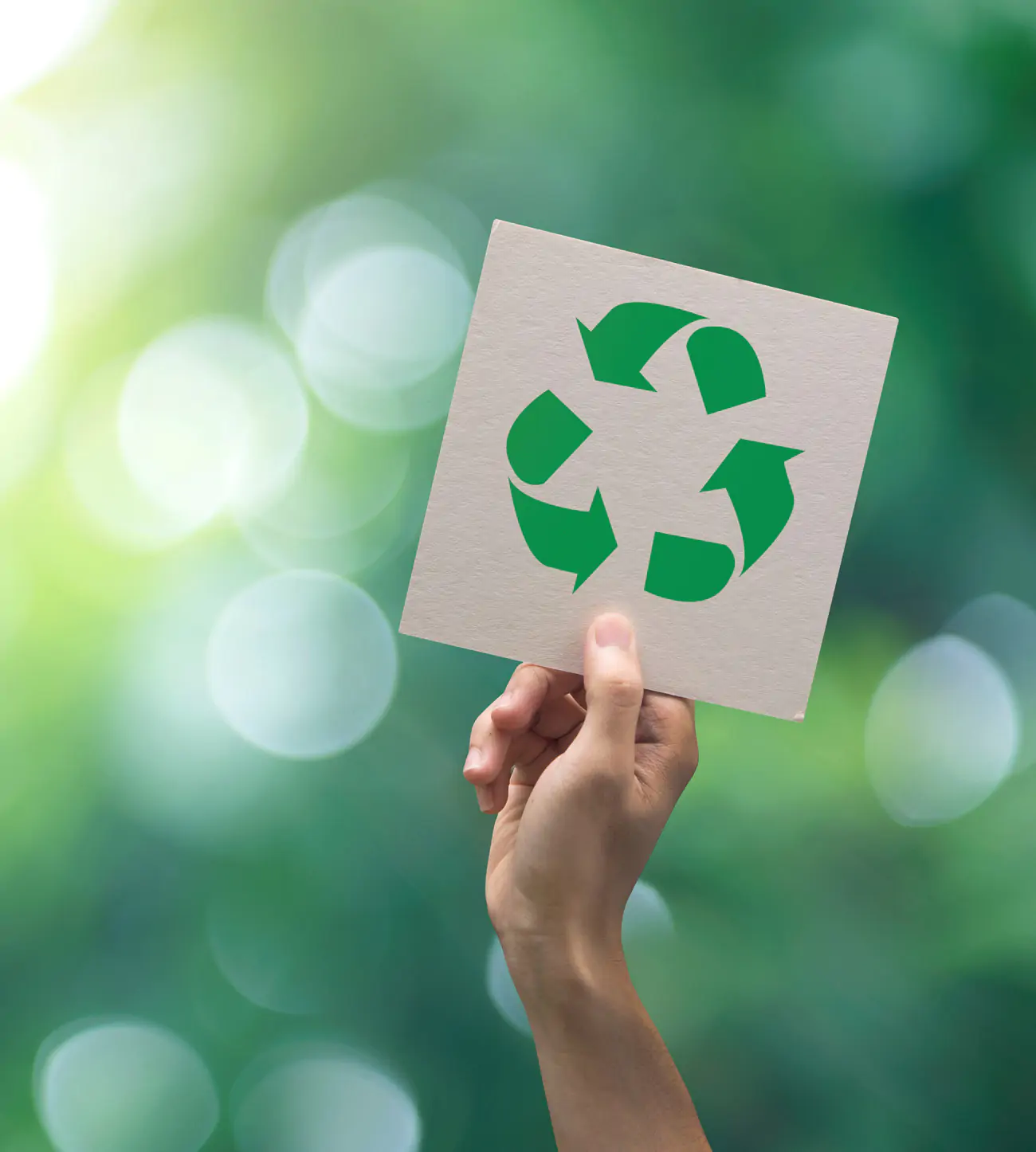 Eine Hand hält ein Schild mit dem Recycling-Symbol