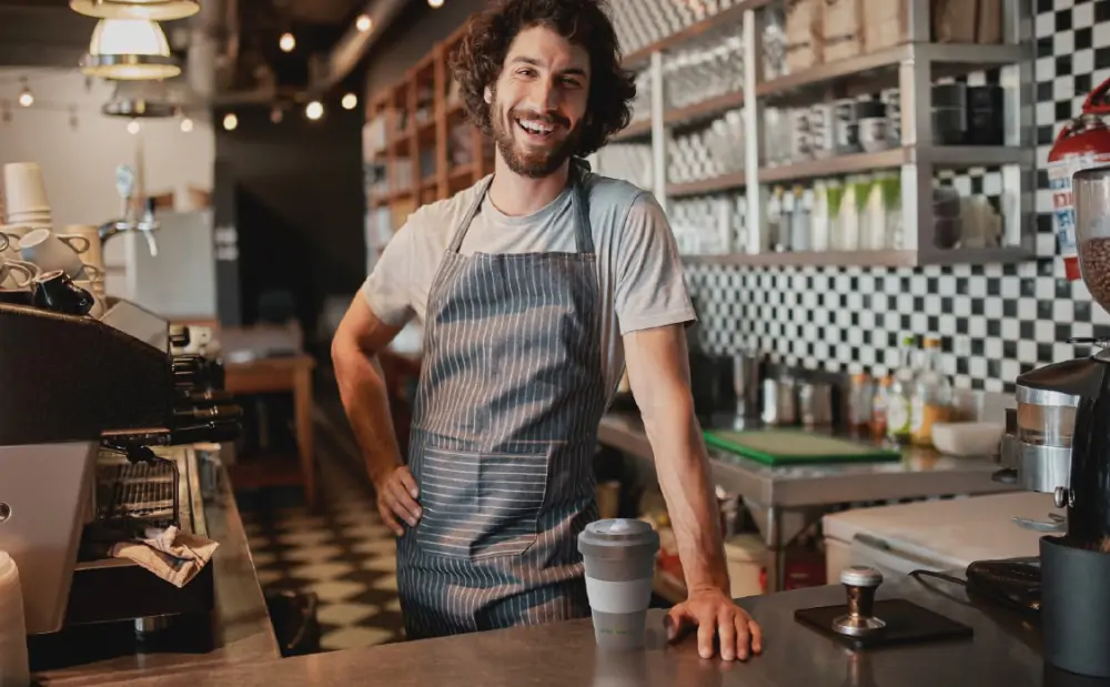 Barista mit einem Mehrweg Kaffeebecher